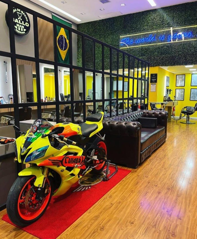 Interior de uma unidade Gallo Man com bandeira do Brasil, letreiro neon e ambiente no padrão da rede